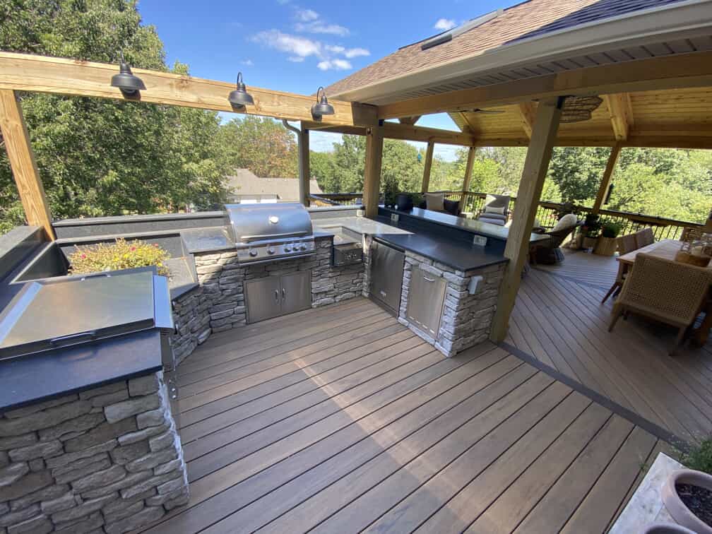 Custom covered outdoor deck that opens to an open air outdoor kitchen